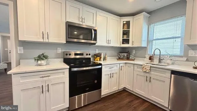 a kitchen with stainless steel appliances granite countertop a sink a stove a dining table and chairs