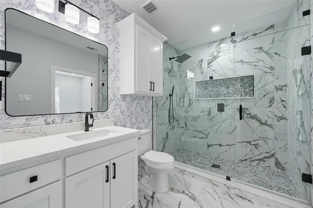 a bathroom with a sink a toilet and shower