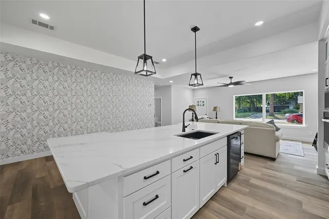 a kitchen with stainless steel appliances granite countertop a sink a window and chairs