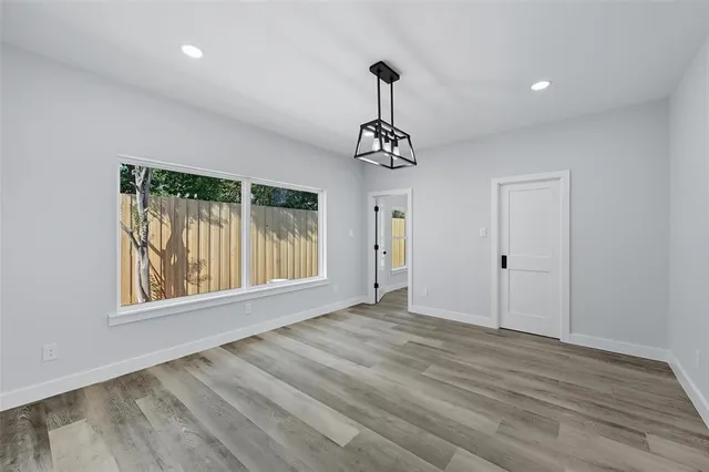 a view of an empty room with window and wooden floor