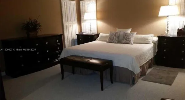 a bedroom with a bed and a lamp on dresser