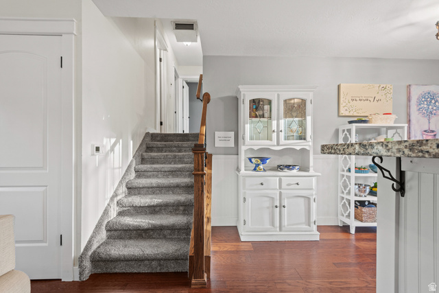 12152 Cinnamon Ridge Road Sandy, UT 84094 - Photo 9 of 34 Elegant foyer showcasing hardwood flooring, a carpeted staircase with wooden handrail, and white wainscoting