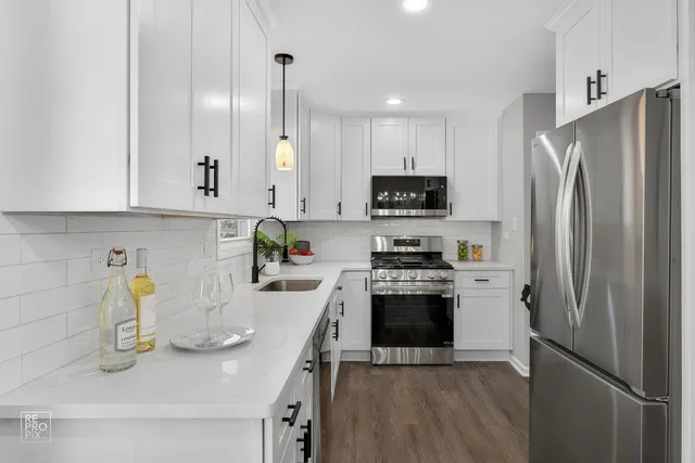 a kitchen with stainless steel appliances a refrigerator a sink a stove a table and chairs