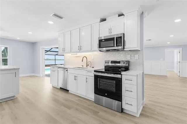 a kitchen with stainless steel appliances granite countertop a stove a sink and a microwave