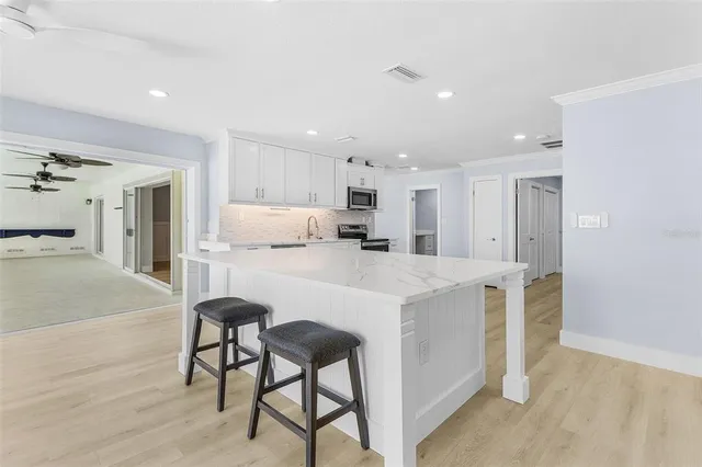 a kitchen with kitchen island a stove a table and chairs in it