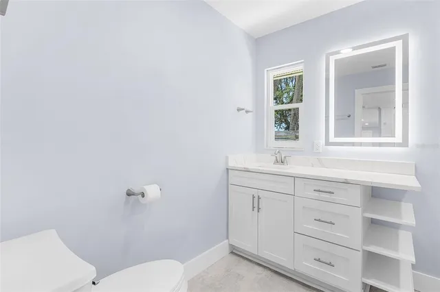 a bathroom with a toilet a sink a mirror and a window