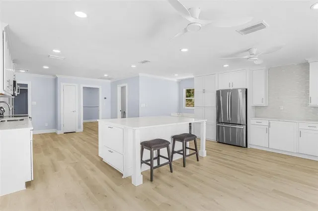 a large white kitchen with stainless steel appliances refrigerator stove microwave and cabinets