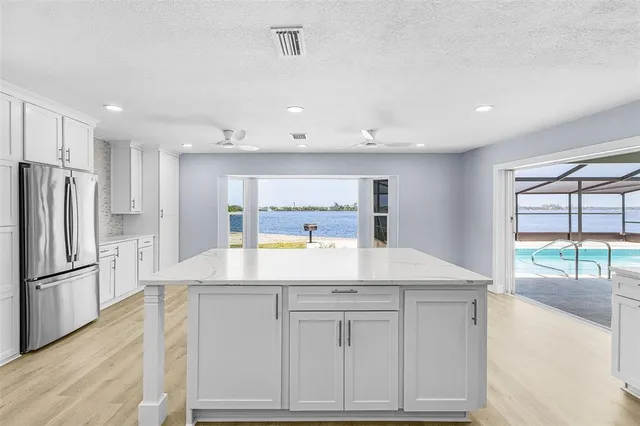 a kitchen with kitchen island white cabinets and refrigerator