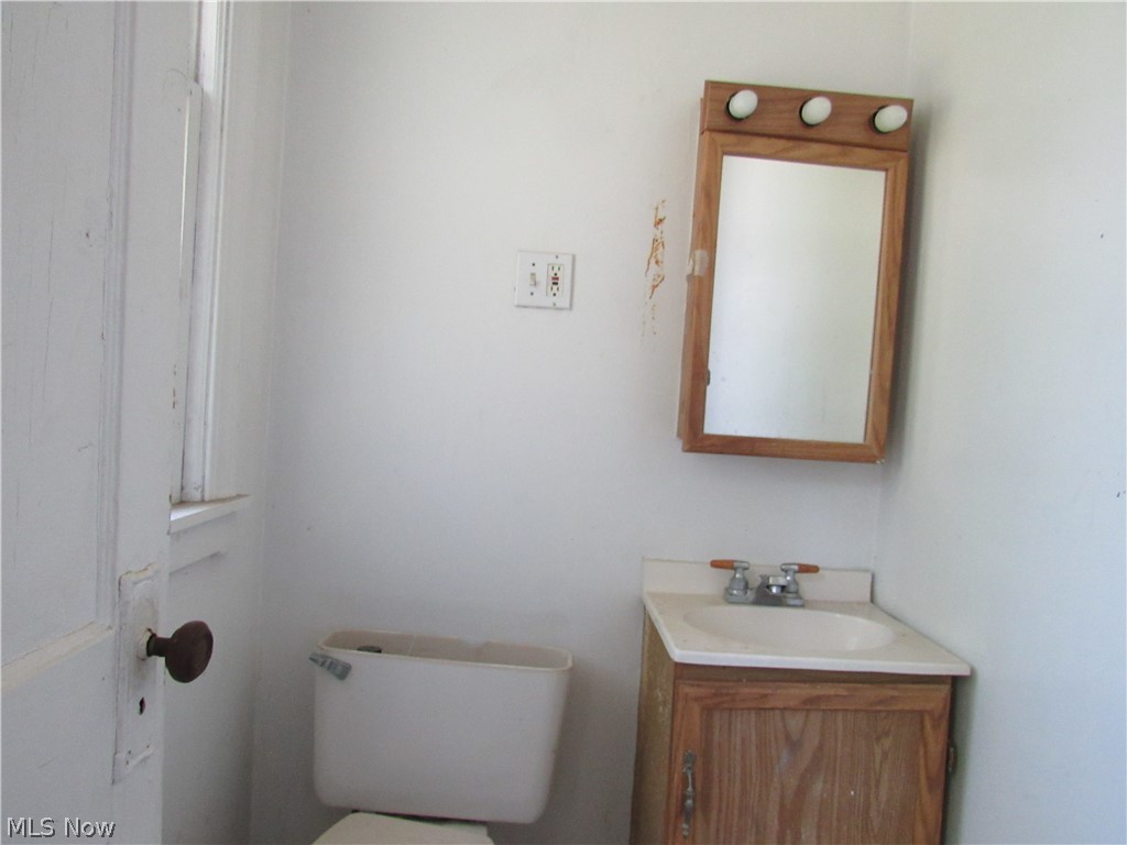 1726 Lee Road Cleveland Heights, OH 44118 - Photo 9 of 36 Bathroom featuring a wood-finish vanity with an integrated sink, a matching medicine cabinet with three-bulb vanity lighting, and a white toilet