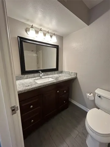 a bathroom with a granite countertop sink toilet and mirror