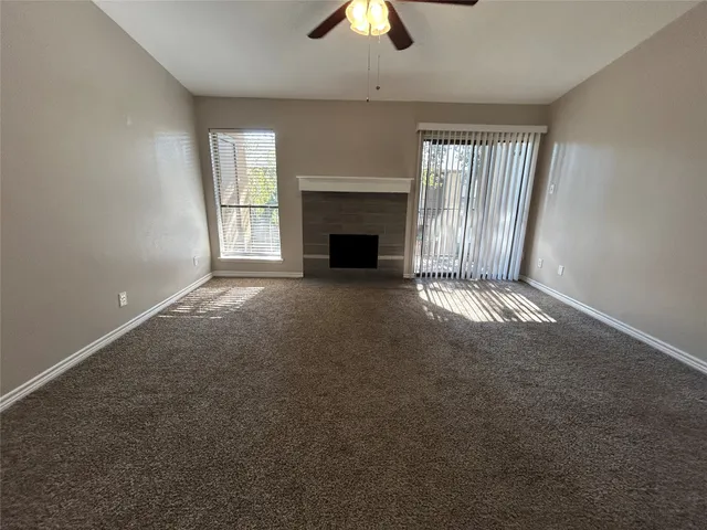 an empty room with windows and fireplace