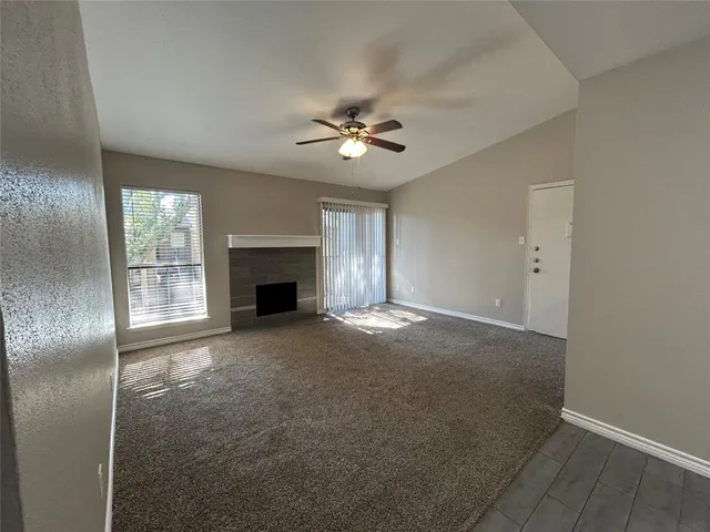 an empty room with windows and fireplace