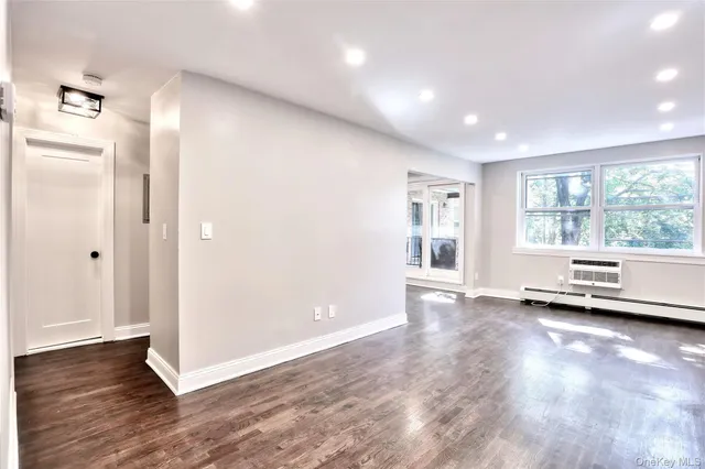 a view of an empty room with a window and wooden floor