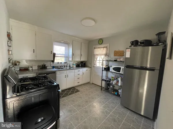 a kitchen with a refrigerator a stove a sink dishwasher and white cabinets with wooden floor