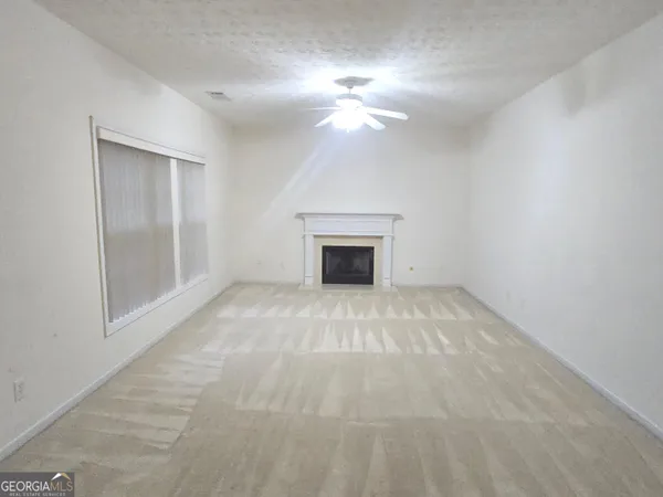 a view of an empty room with a chandelier fan