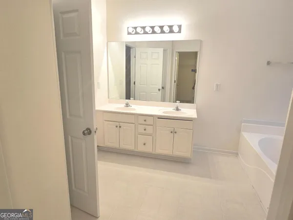 a spacious bathroom with a double vanity sink a mirror and a bathtub