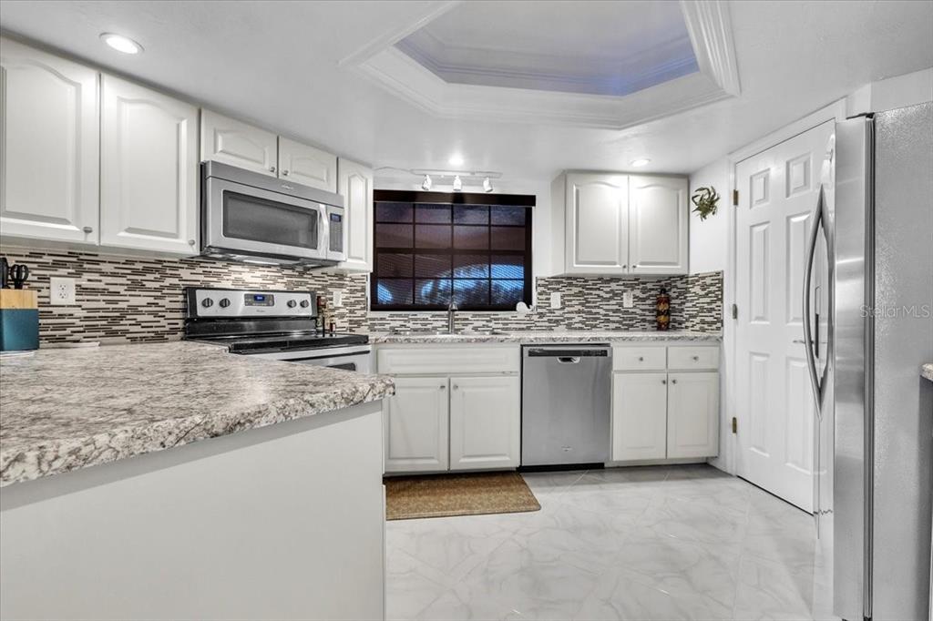 23465 Harbor View Road, Unit 624 Port Charlotte, FL 33980 - Photo 12 of 47 a kitchen with stainless steel appliances granite countertop a refrigerator a stove a sink and white cabinets