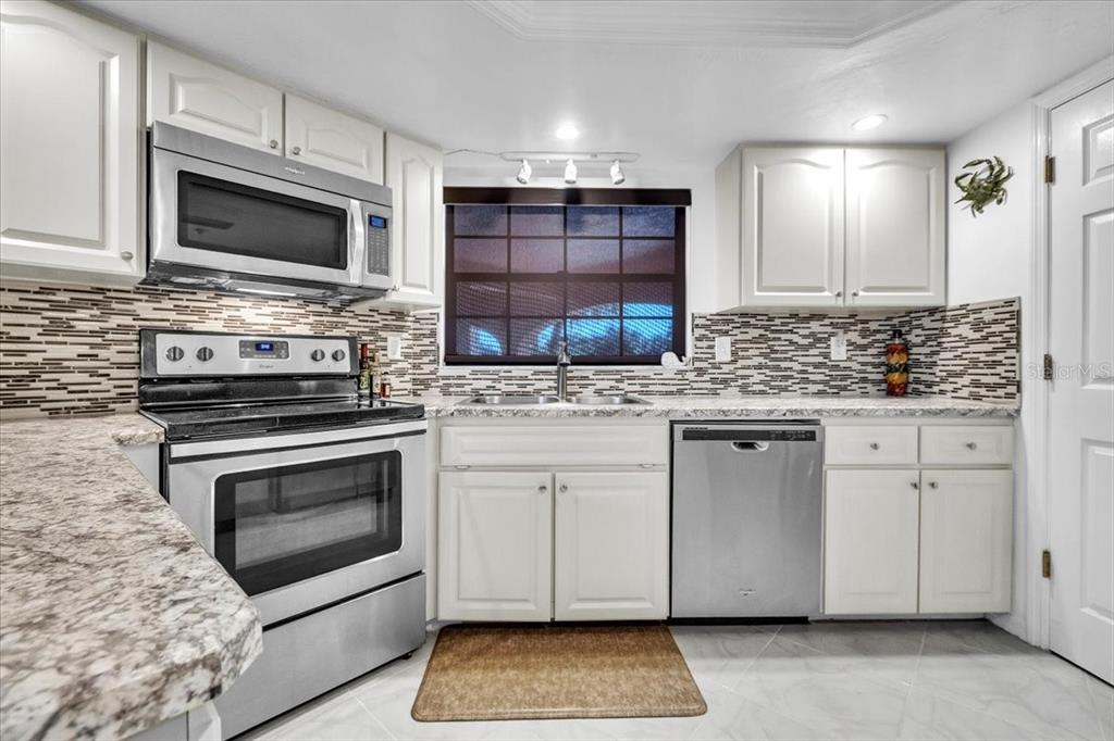 23465 Harbor View Road, Unit 624 Port Charlotte, FL 33980 - Photo 14 of 47 a kitchen with stainless steel appliances granite countertop a stove microwave and oven