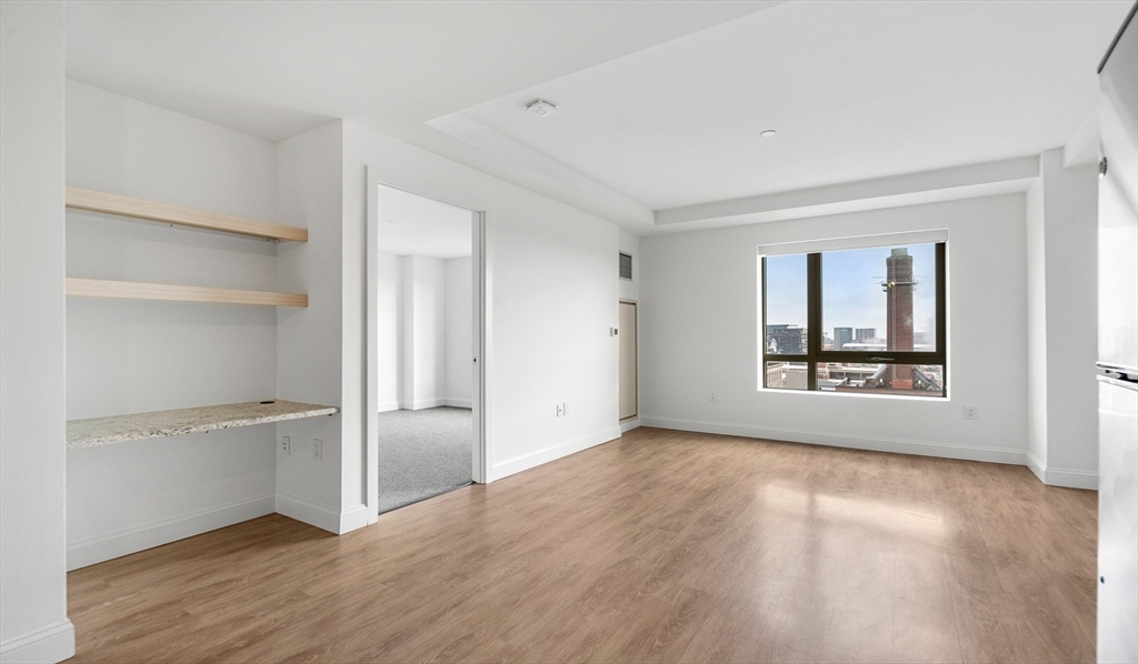 99 Kneeland Street, Unit 1407 Boston, MA 02111 - Photo 3 of 14 a view of an empty room with a window and wooden floor