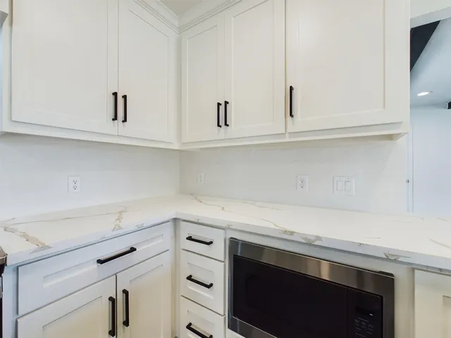 a kitchen with granite countertop white cabinets and a stove