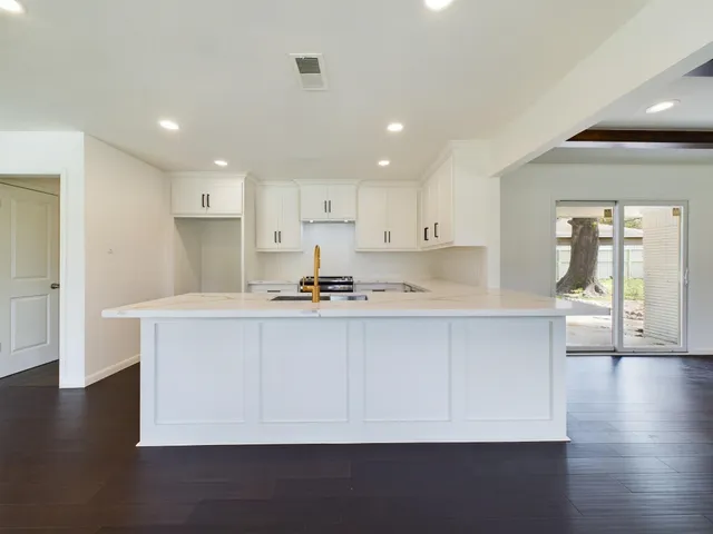 a kitchen with stainless steel appliances a sink a stove a refrigerator and white cabinets