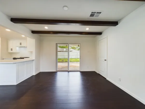 a view of an empty room with wooden floor and a ceiling fan