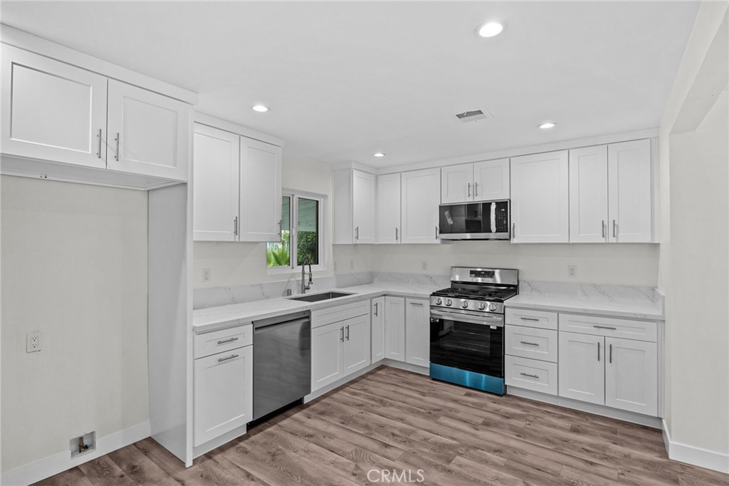 19404 Cheshire Street Rialto, CA 92377 - Photo 9 of 30 a kitchen with stainless steel appliances granite countertop a stove top oven a sink and cabinets