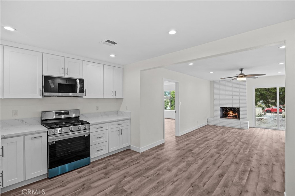 19404 Cheshire Street Rialto, CA 92377 - Photo 10 of 30 a kitchen with granite countertop a stove top oven a sink dishwasher and a refrigerator with wooden floor