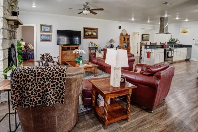 a living room with furniture a flat screen tv and kitchen view