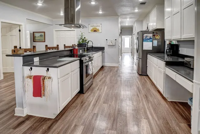 a large kitchen with stainless steel appliances kitchen island granite countertop a stove a sink and a refrigerator