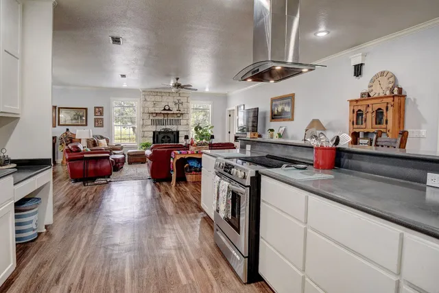 a kitchen with stainless steel appliances granite countertop a stove and a view of living room
