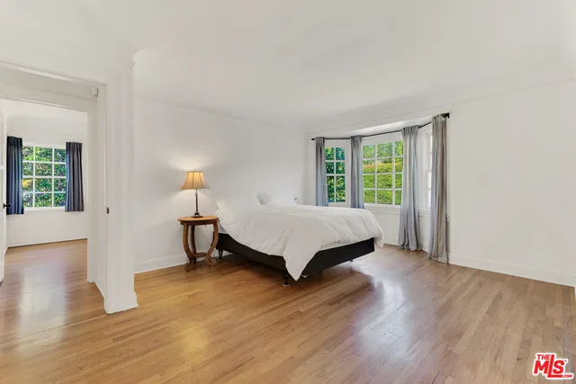 a large white bed sitting in a bedroom next to a window