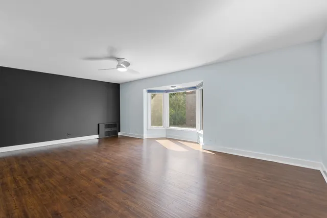 a view of an empty room with a window and wooden floor