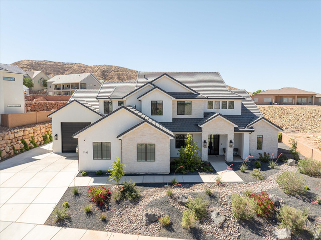 1192 East Corral Way Washington, UT 84780 - Photo 72 of 81 Modern two-story residence featuring white stucco and stone accents, a dark tile roof, and a two-car garage