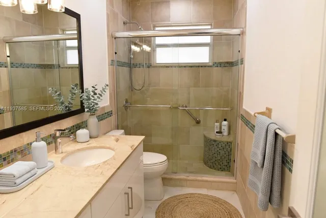a bathroom with a granite countertop sink toilet and shower