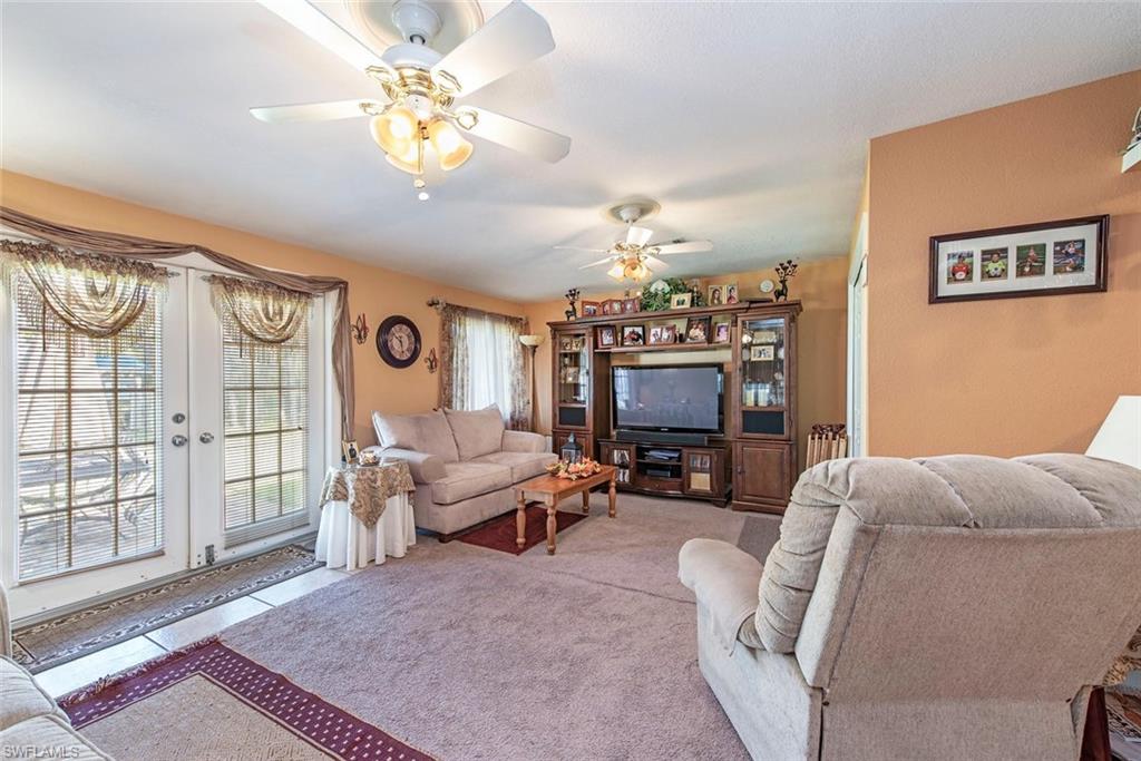 278 Sabal Palm Road Naples, FL 34114 - Photo 2 of 12 a living room with furniture a chandelier and a flat screen tv
