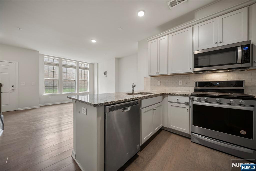 69 Arnold Drive, Unit 5810 Wood-Ridge, NJ 07075 - Photo 15 of 45 a kitchen with stainless steel appliances granite countertop a stove a microwave and a sink