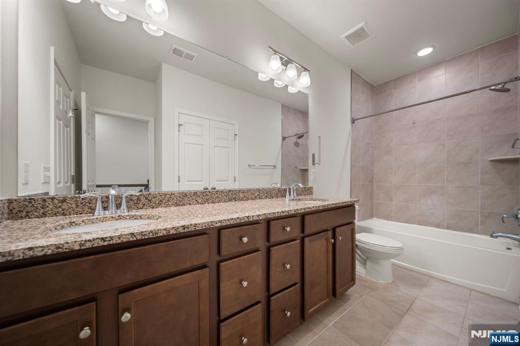 69 Arnold Drive, Unit 5810 Wood-Ridge, NJ 07075 - Photo 23 of 45 a bathroom with a granite countertop bathtub a double vanity sink toilet and a large mirror