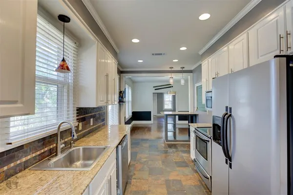 a kitchen with granite countertop a refrigerator and a sink