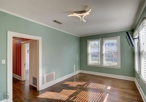 a view of an empty room with a window and wooden floor