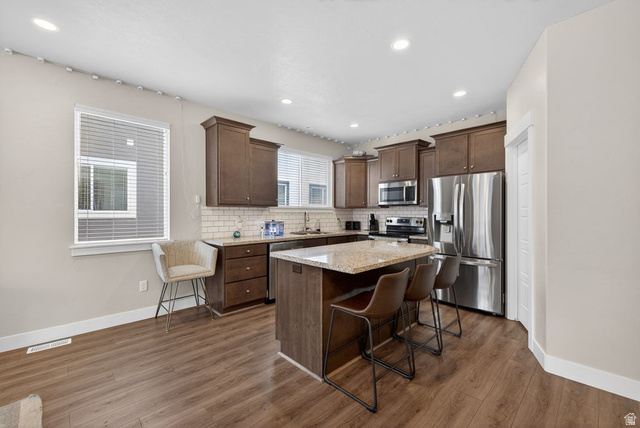 412 McClellan Court Provo, UT 84601 - Photo 4 of 20 Kitchen with a kitchen island, stainless steel appliances, a breakfast bar area, light stone countertops, and dark wood finish cabinetry