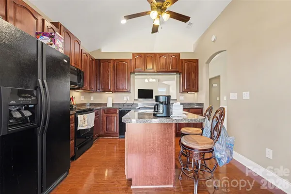 a kitchen with stainless steel appliances granite countertop a refrigerator a stove a sink dishwasher and a microwave oven with wooden floor