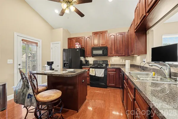 a kitchen with stainless steel appliances granite countertop a sink dishwasher a stove a refrigerator with a dining table and chairs
