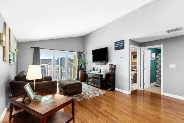 a living room with furniture a flat screen tv and a refrigerator
