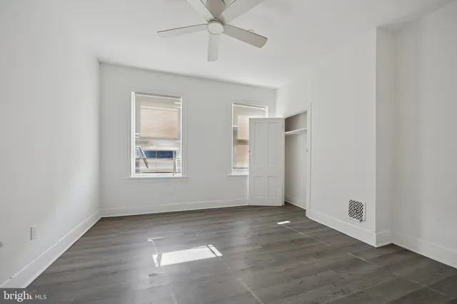 an empty room with wooden floor chandelier fan and windows