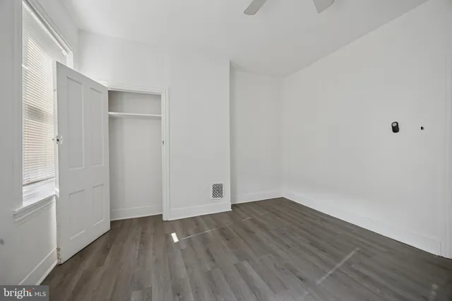 a view of an empty room with wooden floor and closet