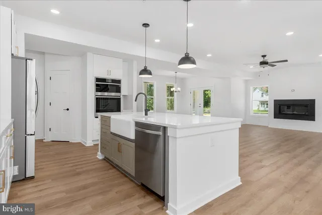 a large kitchen with a large counter top space a sink stainless steel appliances and cabinets