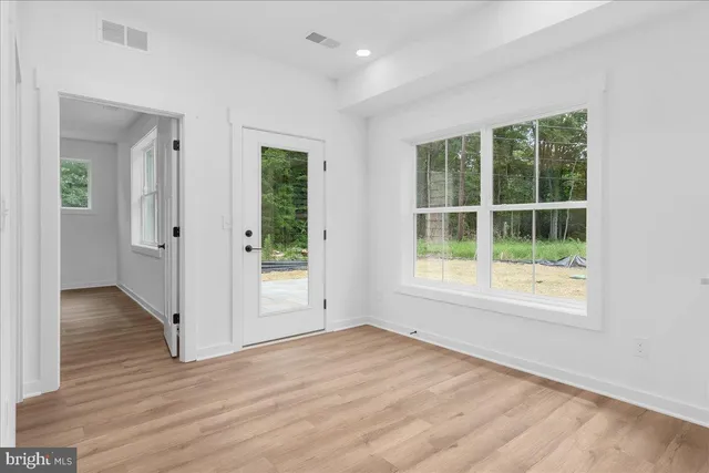 an empty room with wooden floor and windows