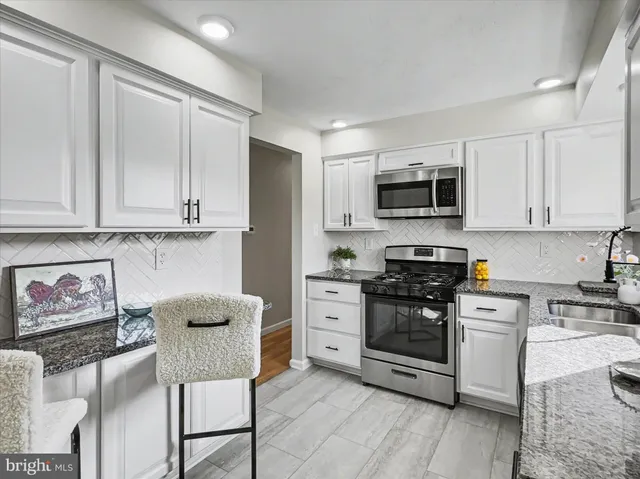 a kitchen with stainless steel appliances granite countertop a stove a sink and a microwave