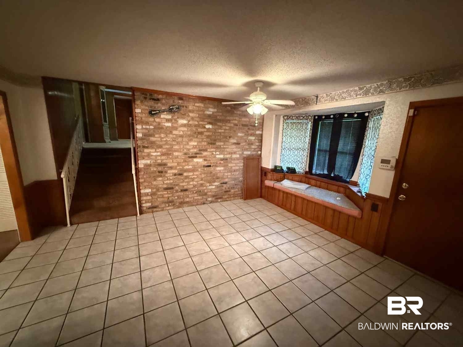 3721 Robertson Court Mobile, AL 36693 - Photo 12 of 22 Unfurnished room featuring brick wall, wainscoting, a ceiling fan, light tile patterned floors, and a textured ceiling